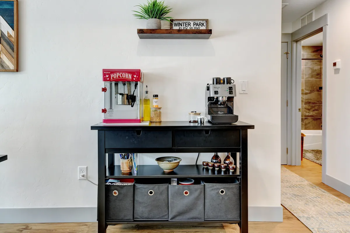 A dedicated beverage and snack station featuring a popcorn machine, coffee maker, and decorative shelving. The setup invites guests to make popcorn for movie night or brew morning coffee, echoing the section's emphasis on daily rituals and special moments.