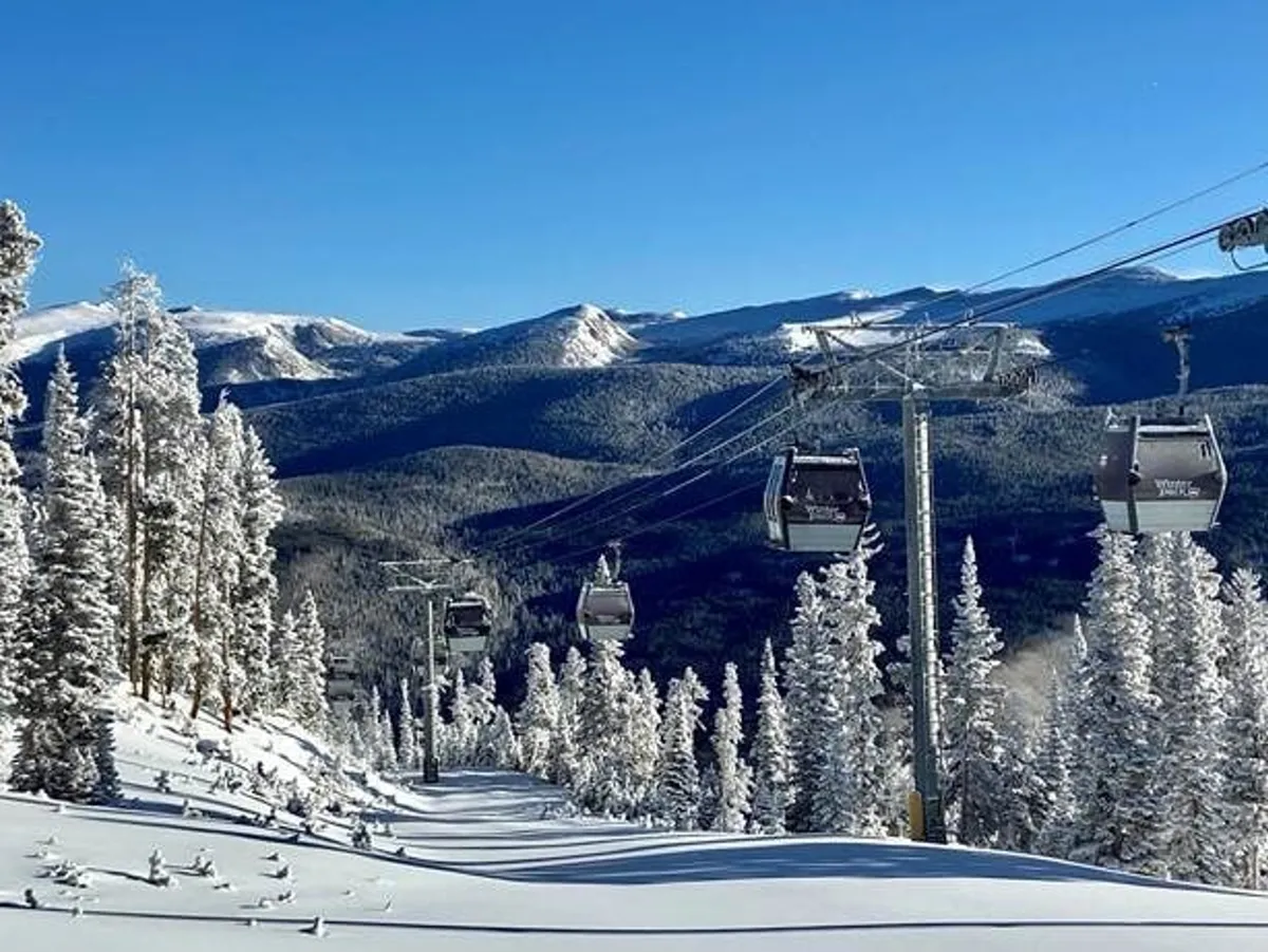 A stunning winter landscape featuring ski lift gondolas, snow-covered trees, and distant mountain peaks. The image conveys both the thrill of winter sports and the serene beauty of the Colorado mountains.